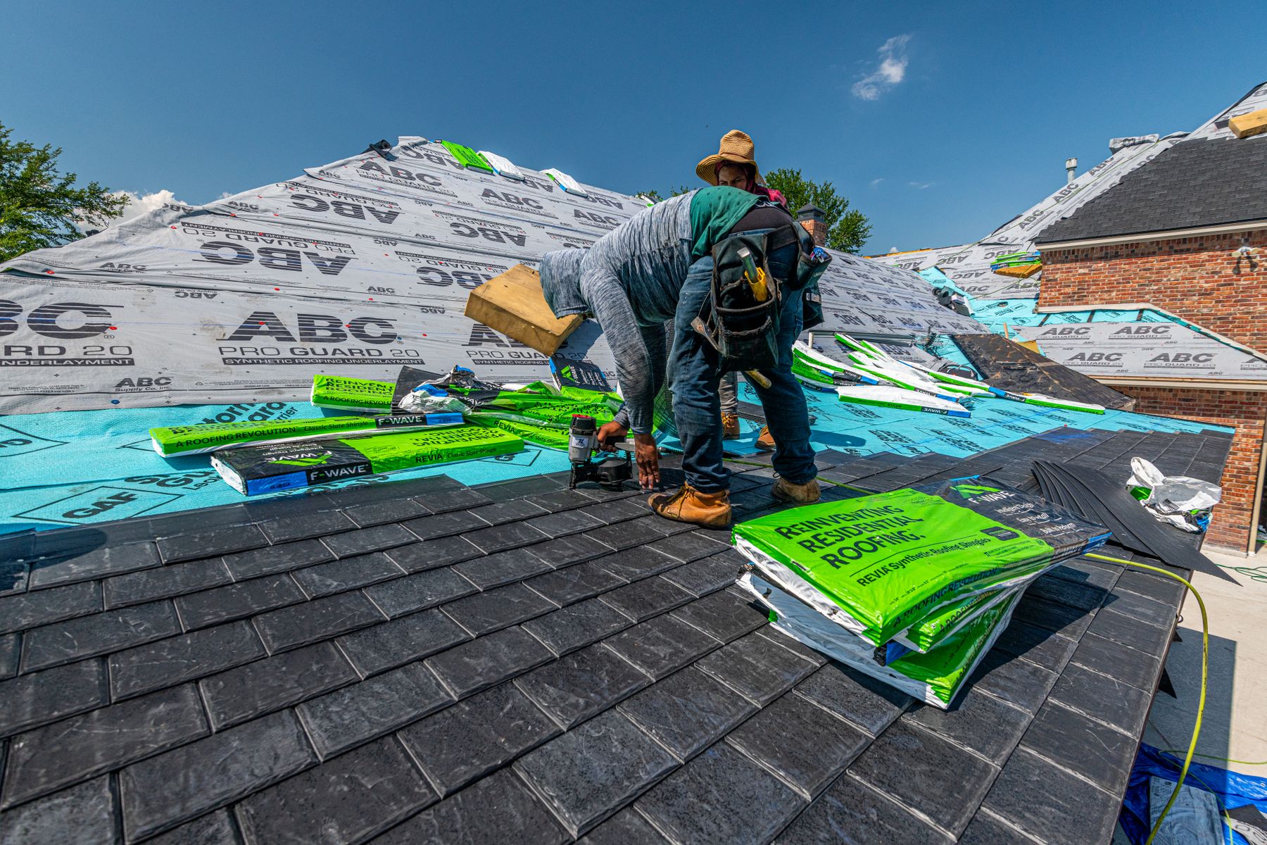 Roofing crew installing new shingles on a brick home in North Texas